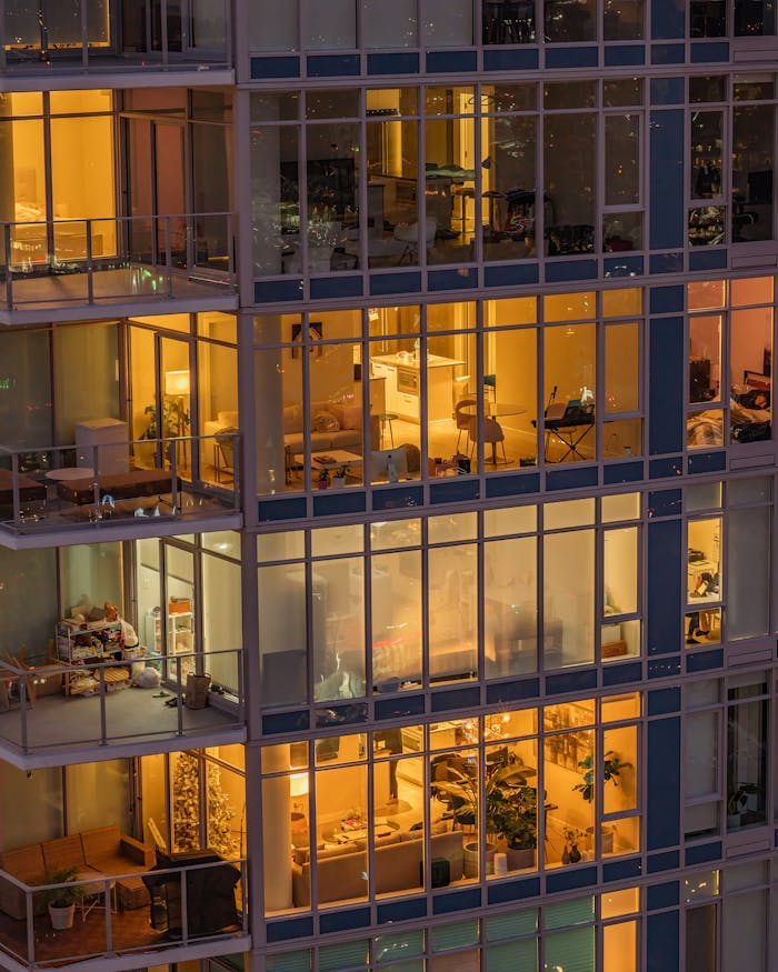 Warmly lit modern apartments in a Vancouver high-rise building at dusk.