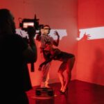 Artistic fashion photo shoot with models posing under dramatic red lighting, showcasing creativity and style.