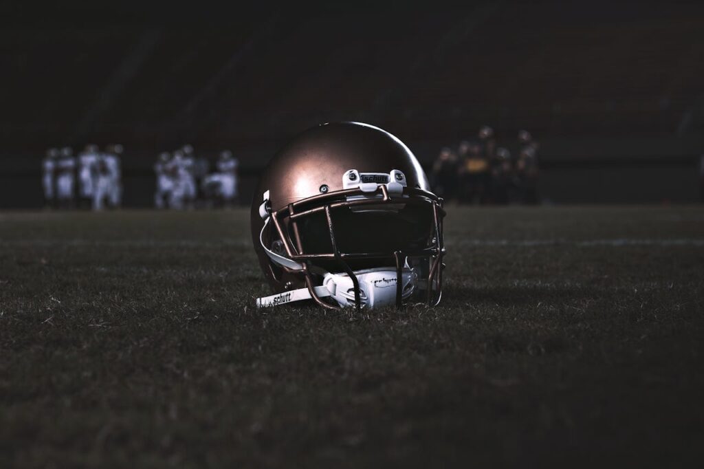 A football helmet placed on a grassy field during a nighttime game, capturing the spirit of sports.