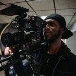 A skilled cameraman filming with a professional video camera in an indoor setting.