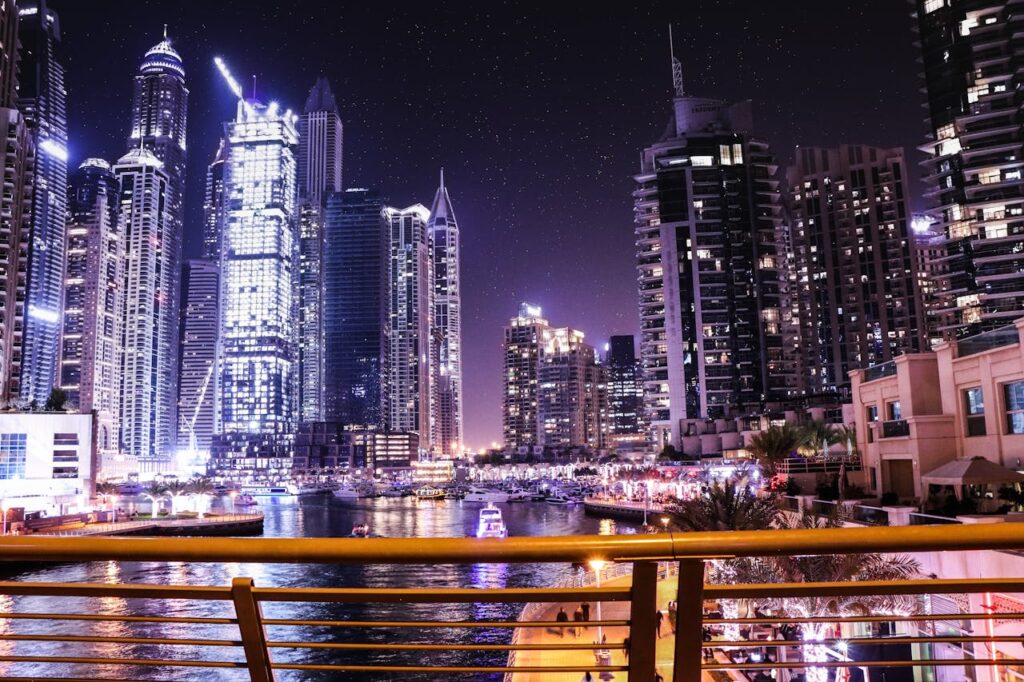 Vibrant night view of Dubai Marina with illuminated skyscrapers reflecting on the water.