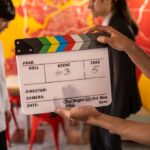 Behind-the-scenes image of a film set with a clapperboard and crew members.
